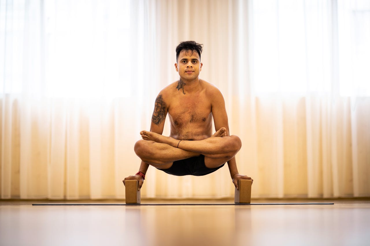Adult man performing advanced yoga pose with focus on balance and strength.