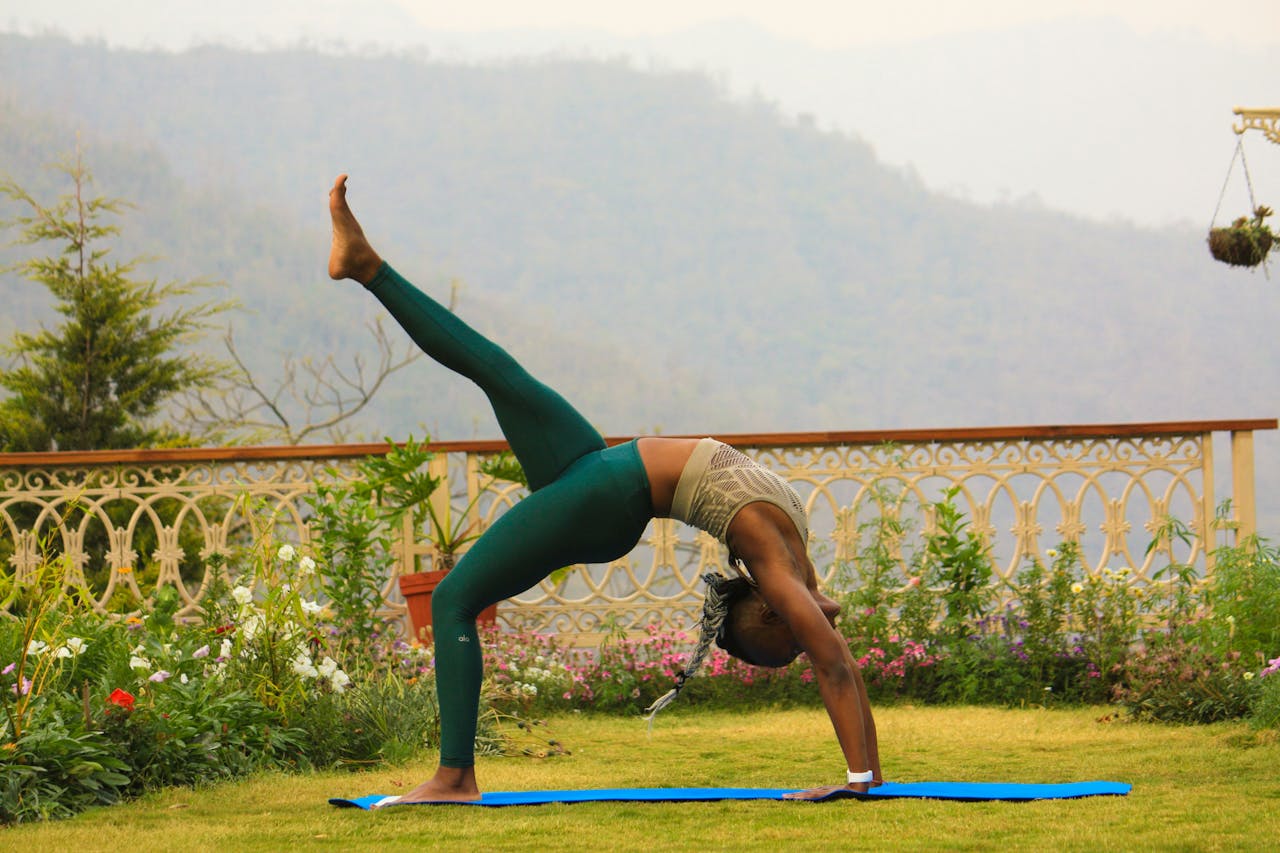 A woman practices yoga outdoors with a scenic mountain backdrop in Rishikesh, India.